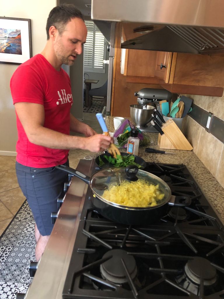 Steven slack cooking eggs and spinach on a large stove.