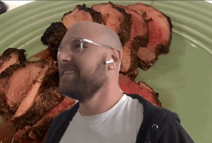 A gif of a White man in a sweatshirt and clear glasses frames shaking his head and gesturing at the camera in front of a virtual background of meat on a green plate